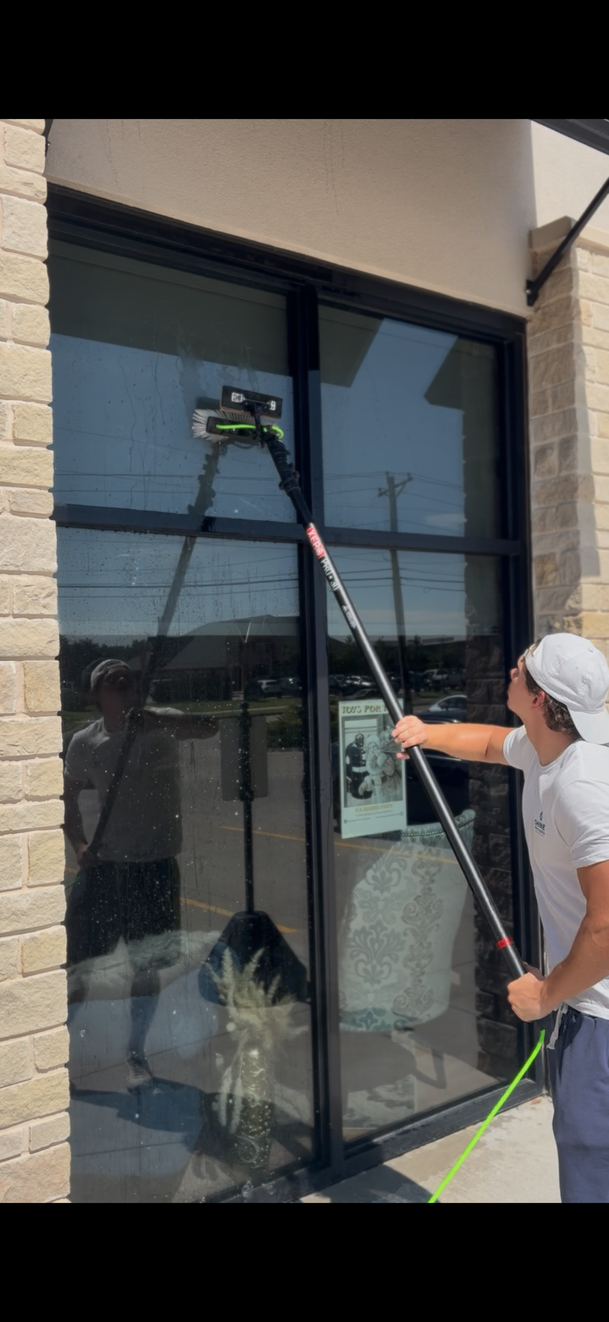 Cleaning tall storefront windows with a water-fed pole